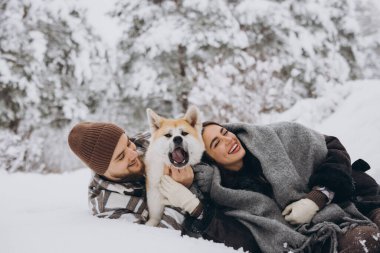 Mutlu genç çift ve akita köpeği kış günü ormanda