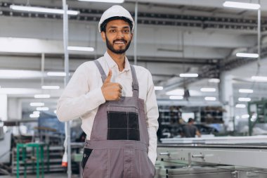 Makine operatörü. Endüstriyel Hintli uluslararası işçi fabrikada çalışıyor. Beyaz şapkalı genç teknisyen..
