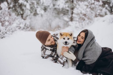 Mutlu genç çift ve akita köpeği kış günü ormanda
