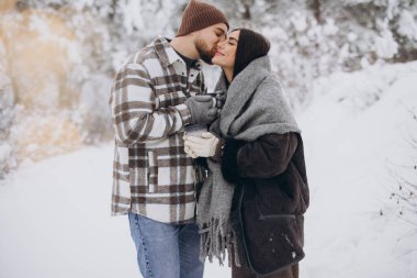 Mutlu çift dinleniyor ve ormanda sıcak çay içiyor. Kışın dağlarda.
