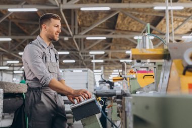 Fabrika erkek sakallı işçi bir CNC değirmen makinesini kopyalama alanı ile programlıyor..