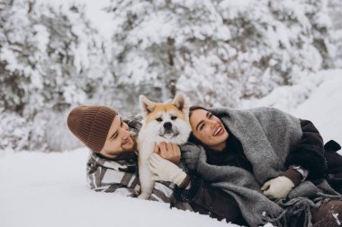 Mutlu genç çift ve akita köpeği kış günü ormanda