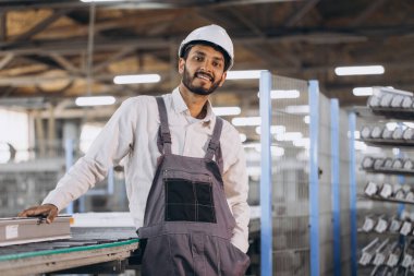 Makine operatörü. Endüstriyel Hintli uluslararası işçi fabrikada çalışıyor. Beyaz şapkalı genç teknisyen..
