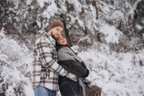 stock image A young happy and loving couple walking in a snowy forest in the mountains