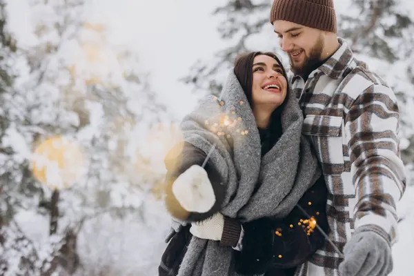 笑顔のロマンチックなカップル 冬の森でスパークラーズとポジショニング 手でベンガルライトを保持 一緒にクリスマス休日を祝う コピースペース — ストック写真