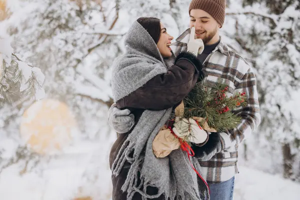 山の雪の冬の森でバレンタインデーの時間を過ごす松の花束に恋するかわいい若いカップル — ストック写真