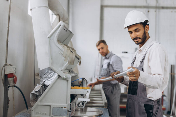 Международная команда, двое рабочих работают на станке на заводе ПВХ окон и дверей