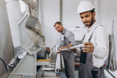 Uluslararası bir ekip, iki işçi PVC pencere ve kapı fabrikasında çalışıyor.