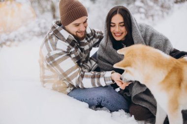 Mutlu genç çift ve akita köpeği kış günü ormanda