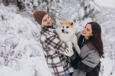Mutlu genç çift ve akita köpek ormanda kışın ve karlı günde