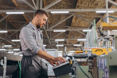 Fabrika erkek sakallı işçi bir CNC değirmen makinesini kopyalama alanı ile programlıyor..