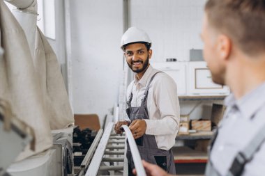 Uluslararası bir ekip, iki işçi PVC pencere ve kapı fabrikasında çalışıyor.