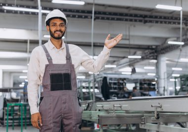 Makine operatörü. Endüstriyel Hintli uluslararası işçi fabrikadaki fotokopi alanında bir şey gösteriyor. Beyaz şapkalı genç teknisyen..
