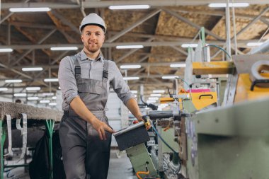 Fabrika erkek sakallı işçi bir CNC değirmen makinesini kopyalama alanı ile programlıyor..