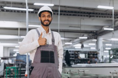 Makine operatörü. Endüstriyel Hintli uluslararası işçi fabrikada çalışıyor. Beyaz şapkalı genç teknisyen..