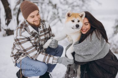 Mutlu genç çift ve akita köpek ormanda kışın ve karlı günde