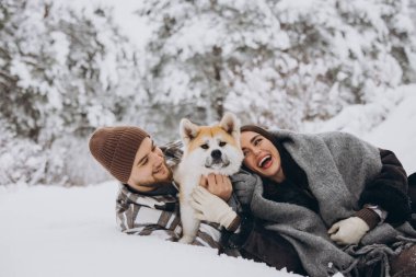 Mutlu genç çift ve akita köpeği kış günü ormanda