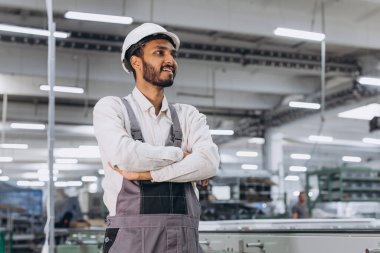 Makine operatörü. Endüstriyel Hintli uluslararası işçi fabrikada çalışıyor. Beyaz şapkalı genç teknisyen..