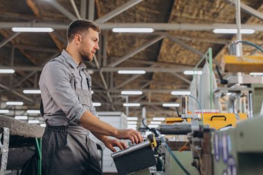 Fabrika erkek sakallı işçi bir CNC değirmen makinesini kopyalama alanı ile programlıyor..