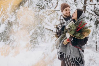 Çam buketine aşık sevimli genç çift Sevgililer Günü 'nde dağlardaki karlı kış ormanlarında vakit geçiriyor.