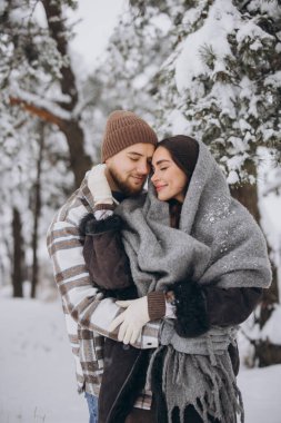 Karlı bir ormanda eğlenen mutlu ve sevgi dolu genç bir çiftin portresi.