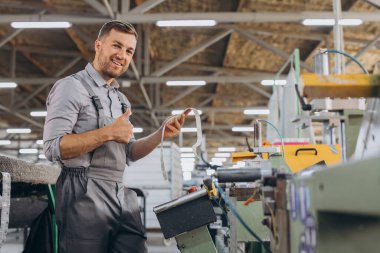 Fabrika erkek sakallı işçi bir CNC değirmen makinesini kopyalama alanı ile programlıyor..