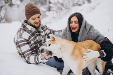 Mutlu genç çift ve akita köpeği kış günü ormanda