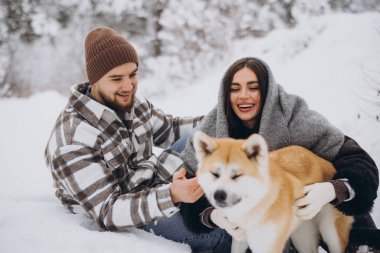 Mutlu genç çift ve akita köpeği kış günü ormanda