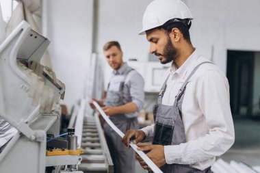 Uluslararası bir ekip, iki işçi PVC pencere ve kapı fabrikasında çalışıyor.