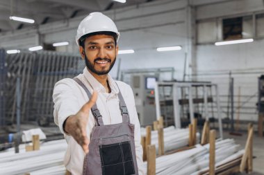 Makine operatörü. Fabrikada sanayi işçisi. Beyaz şapkalı genç teknisyen biriyle tokalaşıyor..