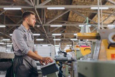 Fabrika erkek sakallı işçi bir CNC değirmen makinesini kopyalama alanı ile programlıyor..