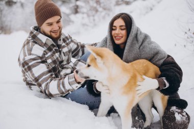 Mutlu genç çift ve akita köpeği kış günü ormanda