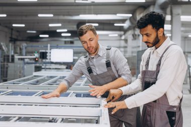 İki erkek uluslararası işçi alüminyum PVC pencere ve kapı üretimi için bir makinede birlikte çalışıyorlar.