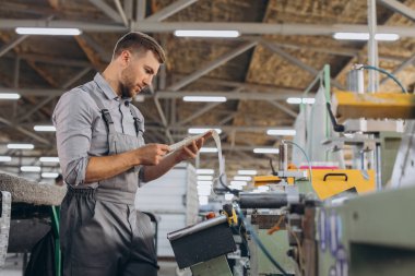 Fabrika erkek sakallı işçi bir CNC değirmen makinesini kopyalama alanı ile programlıyor..