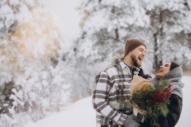 Çam buketine aşık sevimli genç çift Sevgililer Günü 'nde dağlardaki karlı kış ormanlarında vakit geçiriyor.