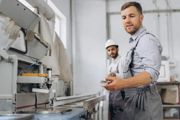 Uluslararası bir ekip, iki işçi PVC pencere ve kapı fabrikasında çalışıyor.