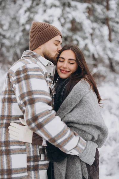 stock image A young happy and loving couple walking in a winter snowy forest in the mountains