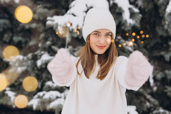 白い編まれた帽子 スカーフ ミトンおよび屋外の時間のスパークラーが付いているセーターを身に着けている笑顔の少女の肖像画 クリスマス休暇 — ストック写真