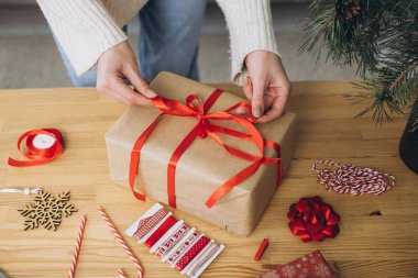 Noel hediyelerini paketleyen kadın eller, kapatın. Dekor elemanları ve ögeleri olan beyaz masada hazırlıksız hediyeler Noel veya Yeni Yıl Kutu Paketi.