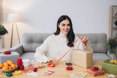 Noel hediye kutularını paketleyen kadın, kapat. Dekor elemanları ve ögeleri olan beyaz masada hazırlıksız hediyeler Noel veya Yeni Yıl Kutu Paketi.