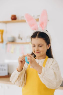 Mutlu Paskalyalar! Renkli yumurta boyayan ve eğlenen güzel bir kız çocuğu. Paskalya günü tavşan kulağı takan sevimli bir kız çocuğu..