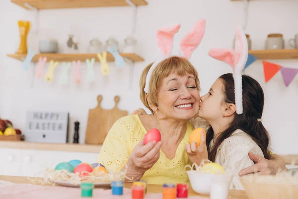 ハッピー イースター 祖母と孫娘がイースターエッグを描いている イースターの準備をしている幸せな家族 可愛いです小さな女の子身に着けているウサギの耳でイースター日 — ストック写真
