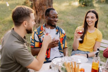 Gitar çalan, şarkı söyleyen, yemek yiyen ve ormanda parti yaparken şarap içen çok ırklı arkadaş grubuyla tanışmak.