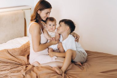 Mutlu genç anne çocuklarıyla yatak odasında vakit geçiriyor.