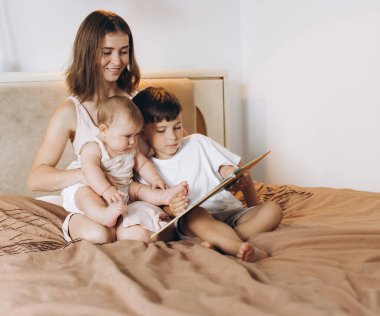 Genç bir anne çocuklarına bir peri masalı okur, bir oğlan ve küçük bir kız bebek