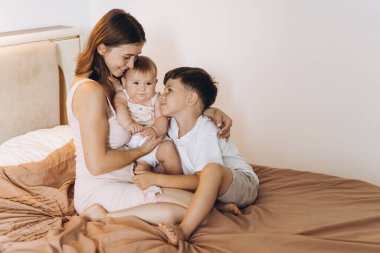 Mutlu genç anne çocuklarıyla yatak odasında vakit geçiriyor.
