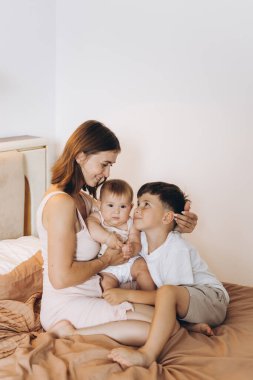 Mutlu genç anne çocuklarıyla yatak odasında vakit geçiriyor.