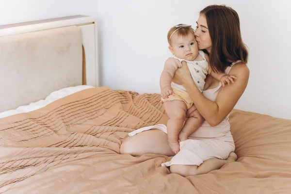 ベッドのベッドで彼女の美しい小さな赤ちゃんの娘と幸せな母親 — ストック写真
