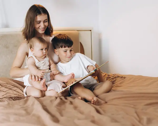 어머니는 그녀의 아이들에게 소년과 소녀를 읽습니다 — 스톡 사진