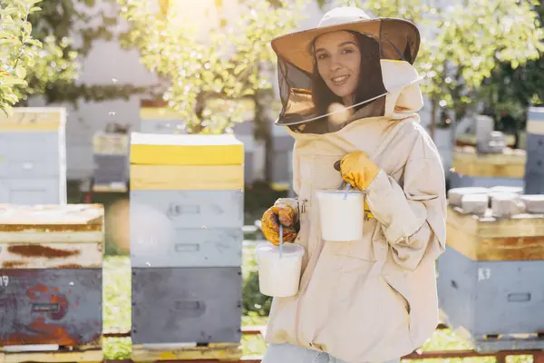 ハッピー笑顔の女性養蜂家 蜂の農場で作られた準備ができた有機蜂蜜を保持しています — ストック写真